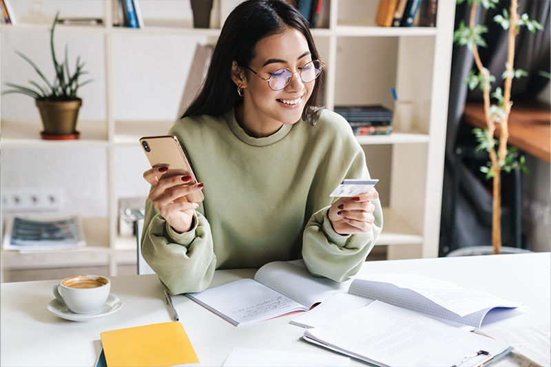Happy optimistic young girl student holding credit card